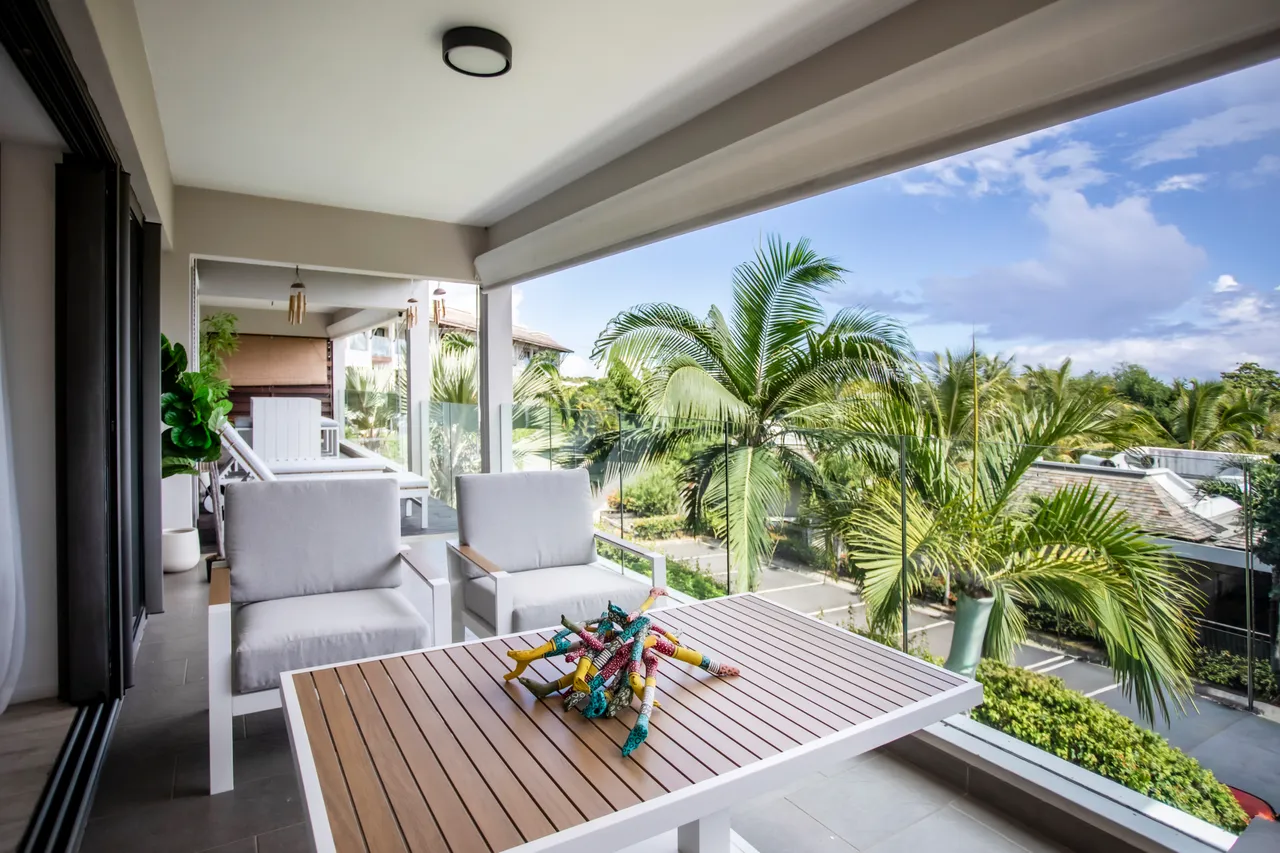 Terrasse avec mobilier moderne offrant une vue sur le jardin luxuriant.  
Végétation environnante ajoutant une touche de verdure au cadre extérieur.  
Éclairage naturel présent grâce aux grandes baies vitrées.  
Espace convivial propice aux repas en plein air et à la détente.  
Ambiance agréable avec une vue dégagée sur le paysage environnant.