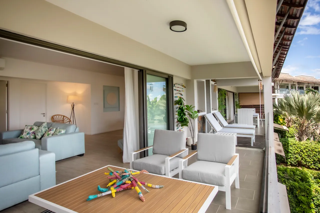 Terrasse avec mobilier d'extérieur et vue sur le jardin.  
Espace de vie ouvert reliant la salle à manger et le salon.  
Fenêtres coulissantes permettant une circulation d'air agréable.  
Éclairage naturel grâce aux grandes baies vitrées.  
Mobilier sobre et contemporain pour un agencement fonctionnel.