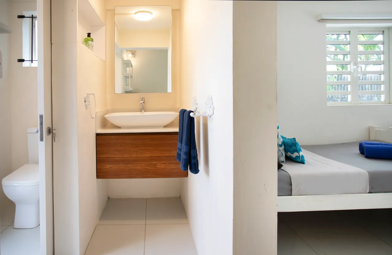 Salle de bain épurée avec lavabo en bois et accessoires en acier inoxydable. Espace lumineux et fonctionnel avec carrelage au sol.