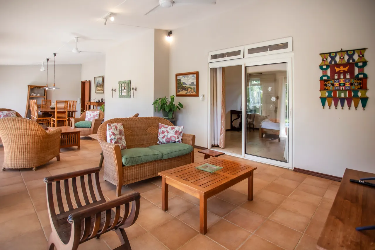Espace de vie avec mobilier en rotin et table basse en bois. Accès direct au jardin et à la piscine.