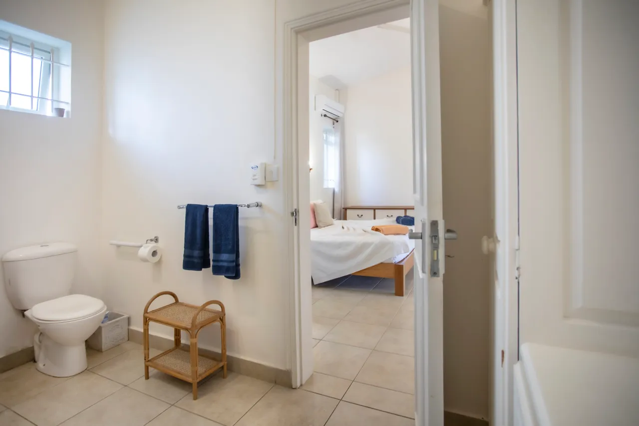 Salle de bain fonctionnelle avec toilettes, douche et rangement en bois. Éclairage naturel provenant d'une fenêtre.