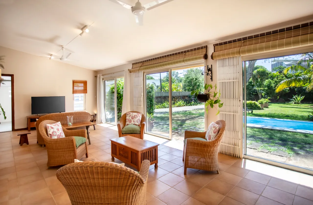 Espace ouvert avec de grandes baies vitrées, offrant une vue sur le jardin et la piscine.