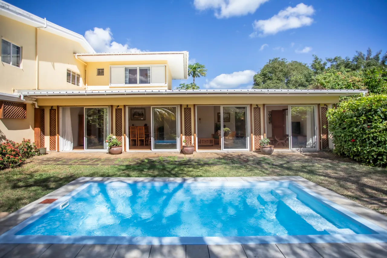 Espace extérieur avec piscine et jardin, entouré de verdure. Baies vitrées pour une vue dégagée.