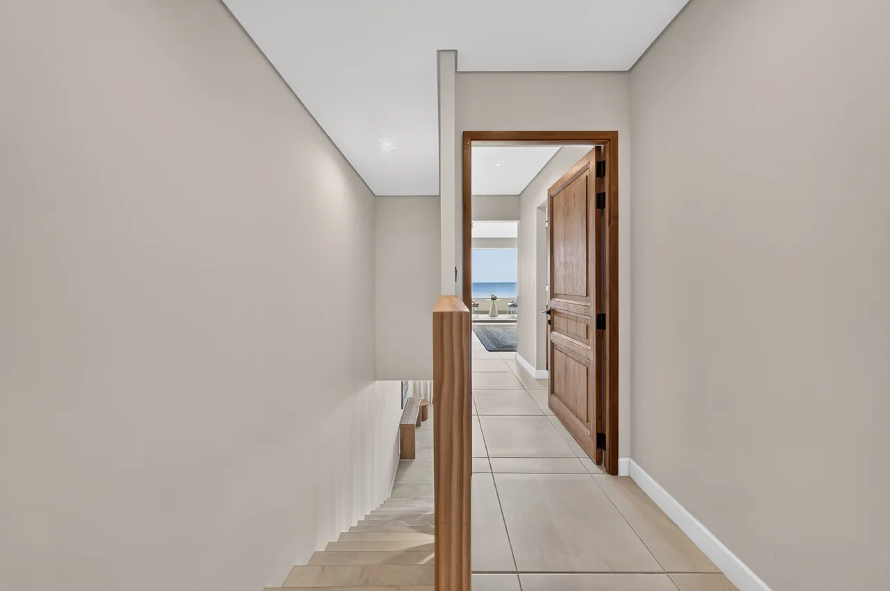 Couloir carrelé et porte ouverte sur une pièce lumineuse.