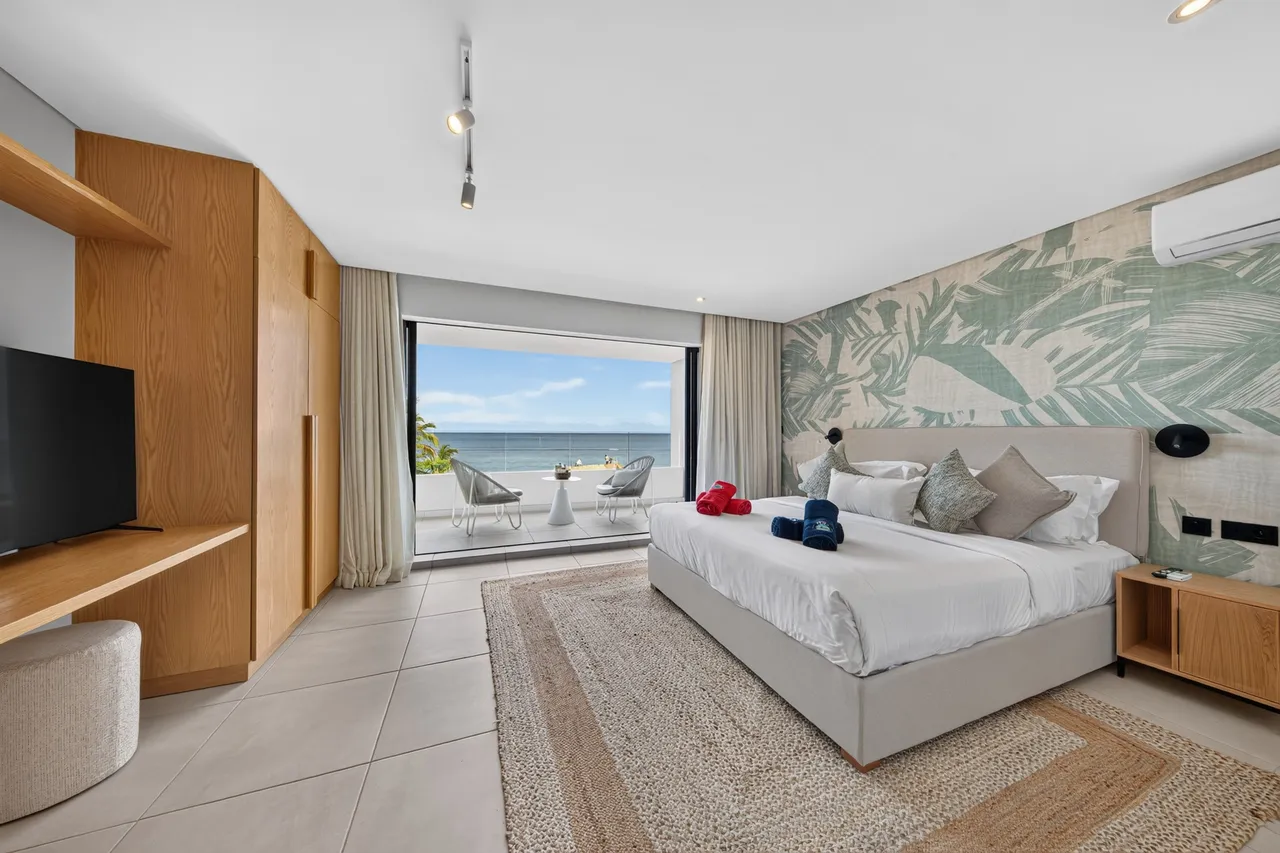 Chambre avec lit double, rangements en bois et ouverture sur la mer.